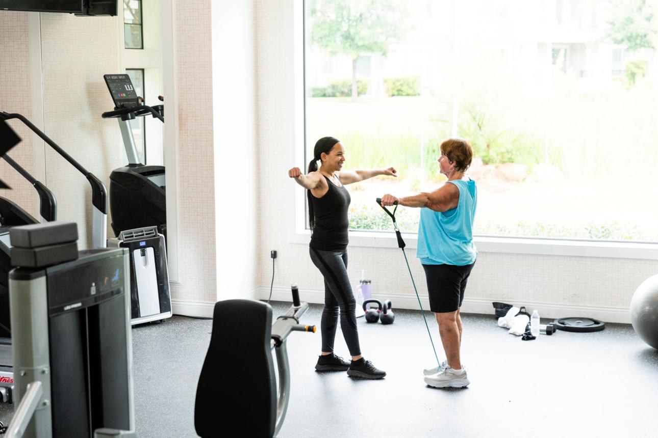 A personal trainer guiding an older client through a resistance-band exercise