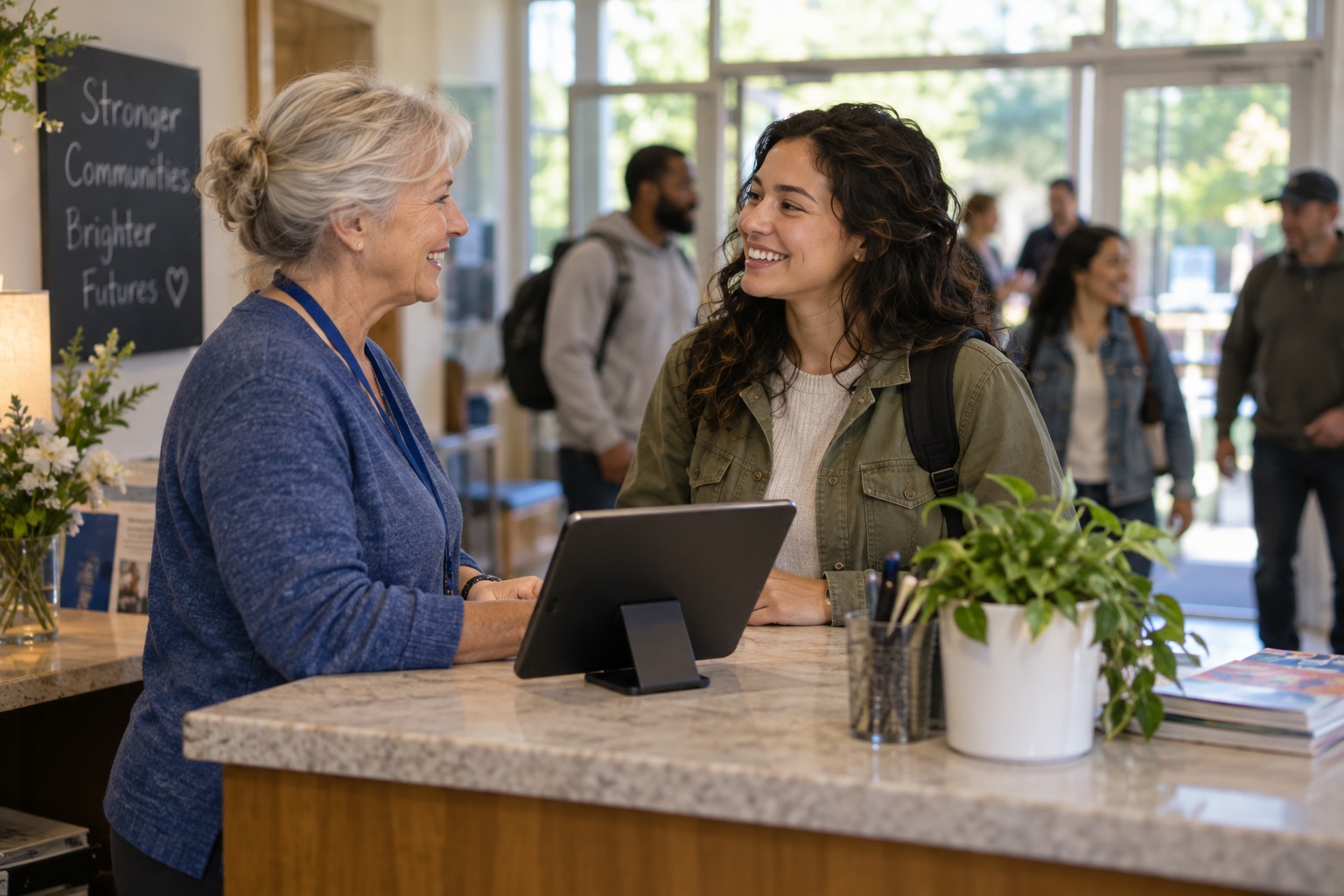 A volunteer welcomes a participant at a tablet-equipped program check-in desk